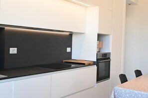 Eine moderne Küche mit weißen Schränken, einer schwarzen Arbeitsplatte und einem eingebauten Ofen.