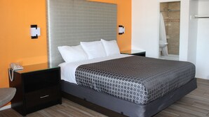 A hotel room with a bed, a nightstand, a telephone, and a shower area. - Torch Lite Lodge (Yuma)