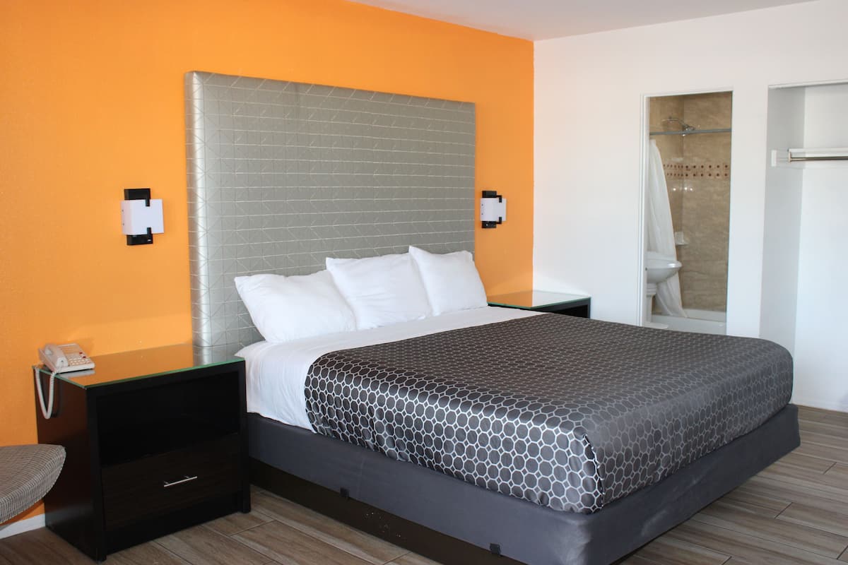 Une chambre d’hôtel comprenant un lit, une table de chevet, un téléphone et un espace douche.