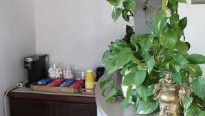 A kitchen counter with a coffee maker, a fruit tray, and a decorative Buddha statue. - Torch Lite Lodge (Yuma)