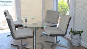A modern indoor seating area with a glass table and four chairs. - Torch Lite Lodge (Yuma)