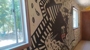 A hallway with a mural on the wall, large windows, and a door leading to another room. - Hostal Nahuel Ray (Pucon)