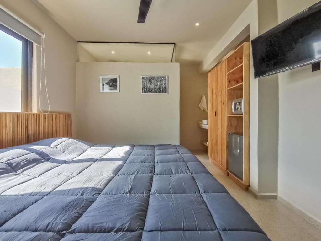 A bedroom with a large bed, wooden wardrobe, and a flat-screen TV.