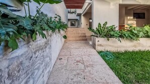 A narrow pathway leading to a staircase in a modern building with concrete walls and green plants. - CASA ULA - Cancun (Cancun)