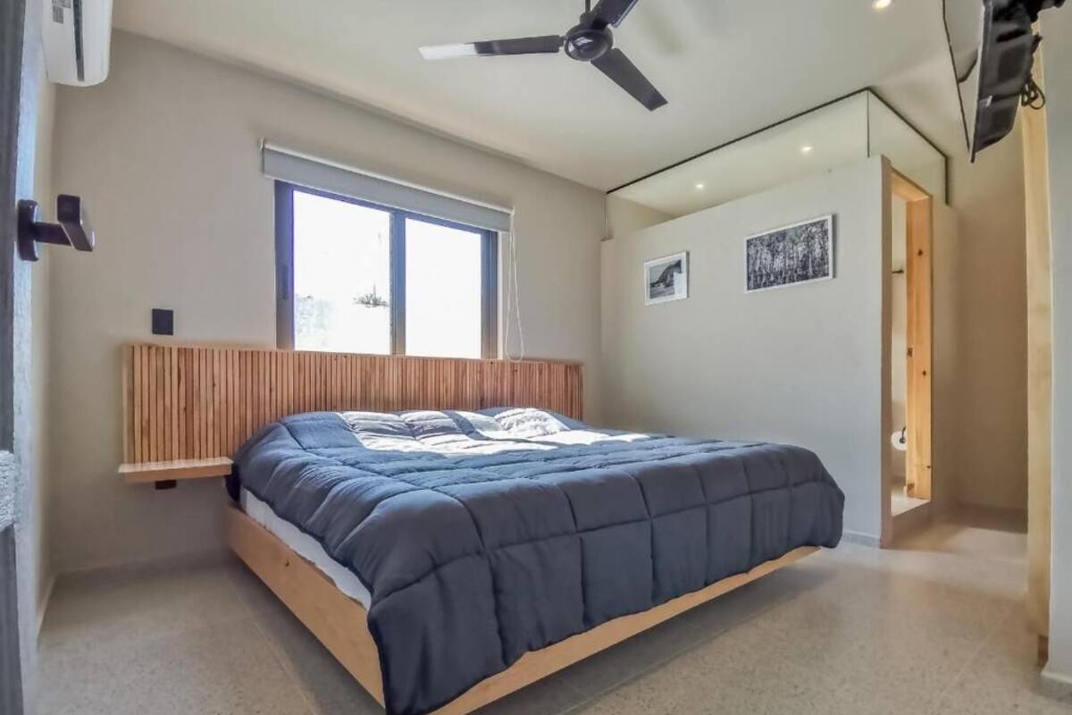 A bedroom with a bed, a ceiling fan, a window, and a door.