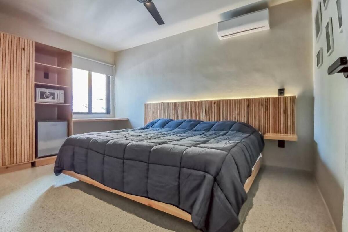 A bedroom with a bed, wooden paneling, a ceiling fan, and an air conditioning unit.