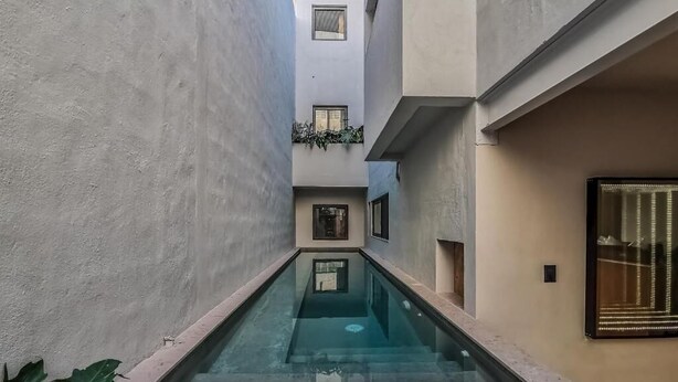 A narrow, enclosed courtyard with a central glass pool, surrounded by buildings with balconies and a decorative light fixture. - CASA ULA - Cancun (Cancun)