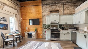 A modern kitchen with white cabinets, stainless steel appliances, and a wooden accent wall. - Only Groundfloor access Downtown Laurel - G (Laurel)