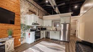A modern kitchen with white cabinets, stainless steel appliances, and a wooden accent wall. - Only Groundfloor access Downtown Laurel - G (Laurel)