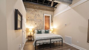 A bedroom with a bed, a brick wall, a door, and a radiator. - Only Groundfloor access Downtown Laurel - G (Laurel)