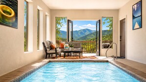 A swimming pool with a view of mountains, a seating area with chairs and a table, and a door leading outside. - Million $ View|Pool Table|Indr Pool|Games (Sevierville)