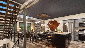 A modern kitchen with a large island, stainless steel appliances, and a rustic wall art piece. - Million $ View|Pool Table|Indr Pool|Games (Sevierville)