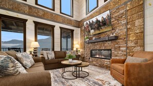 A spacious living room with a stone fireplace, large windows, and a cozy seating area. - Million $ View|Pool Table|Indr Pool|Games (Sevierville)