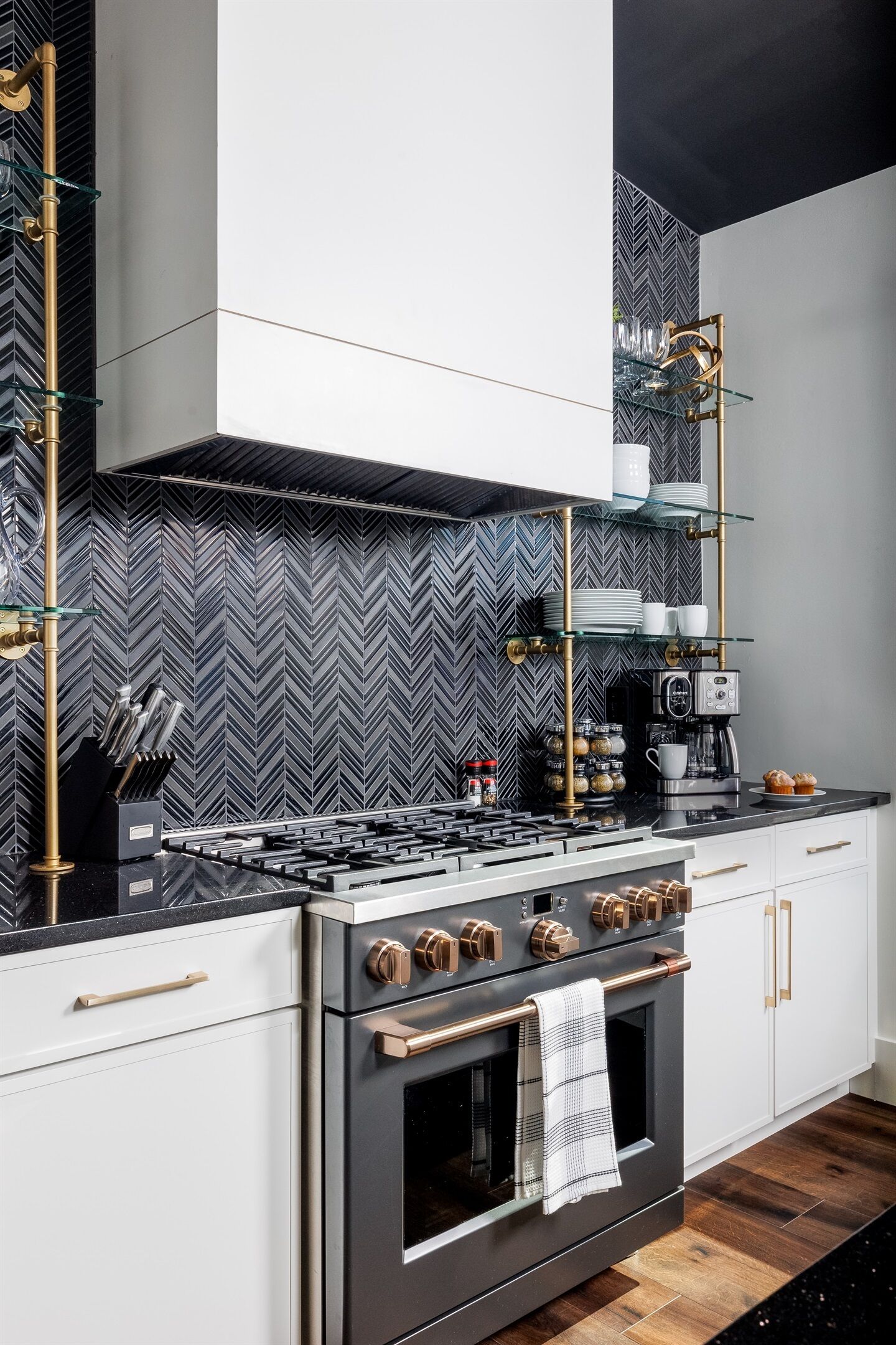 Une cuisine moderne avec un dosseret en motifs chevrons noir et blanc, des appareils en acier inoxydable et une machine à café.