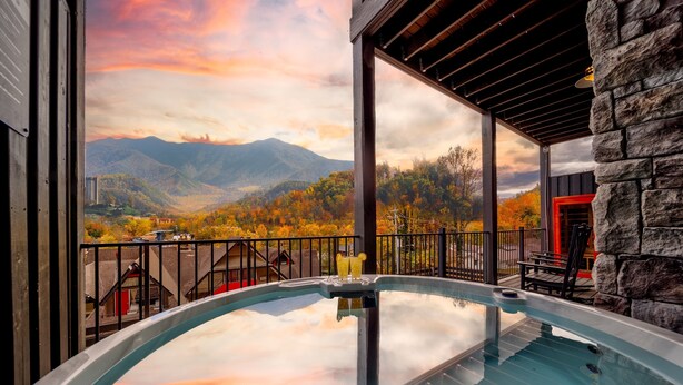 A hot tub with a mountain view, stone walls, and a red door. - 5min walk to Gatlinburg|Mtn View|Sauna|Indr Pool|Game| (Gatlinburg)