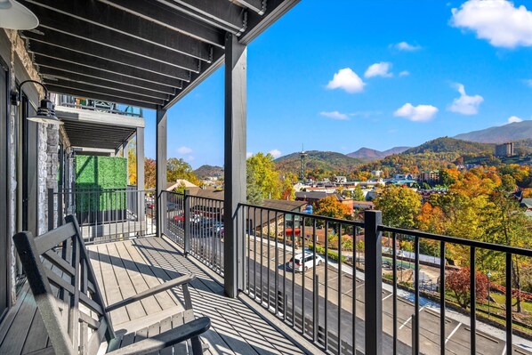 A balcony with a view of a parking lot and a hilly landscape.