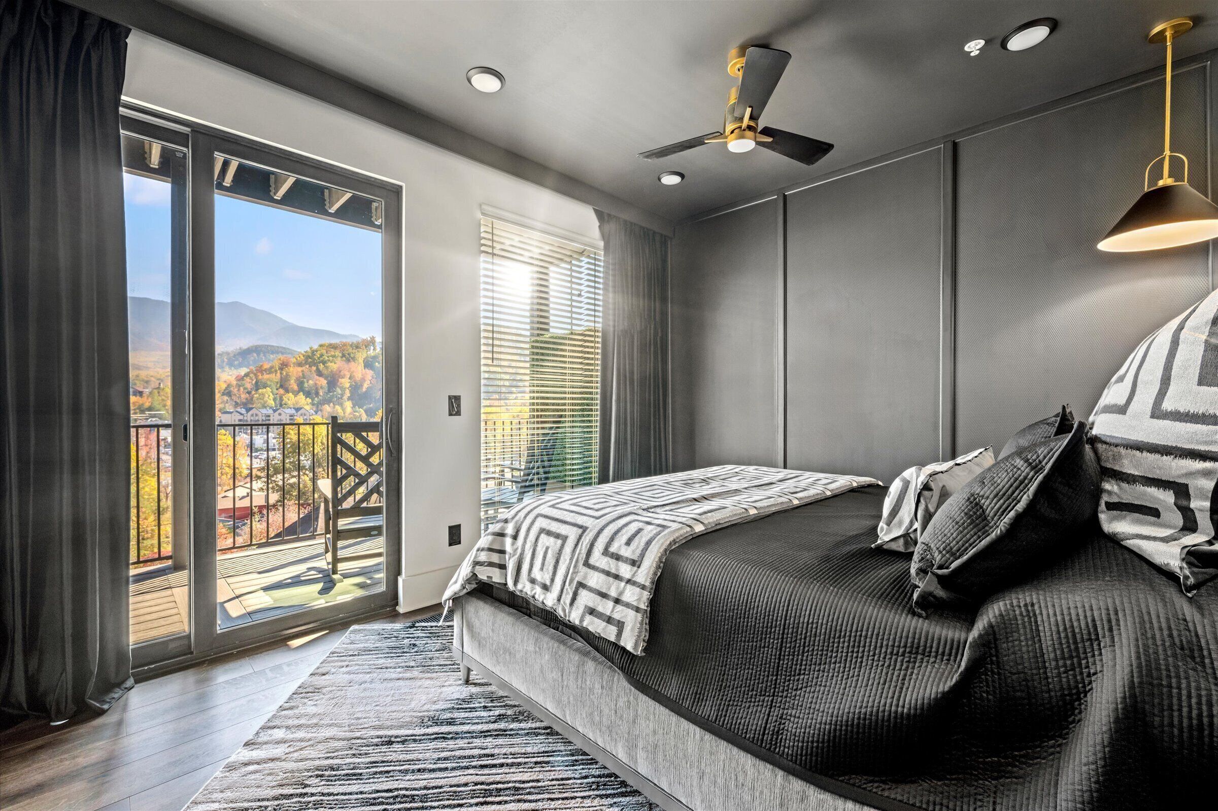 Camera da letto con un letto grande, un ventilatore a soffitto e vista su un balcone con ringhiera.