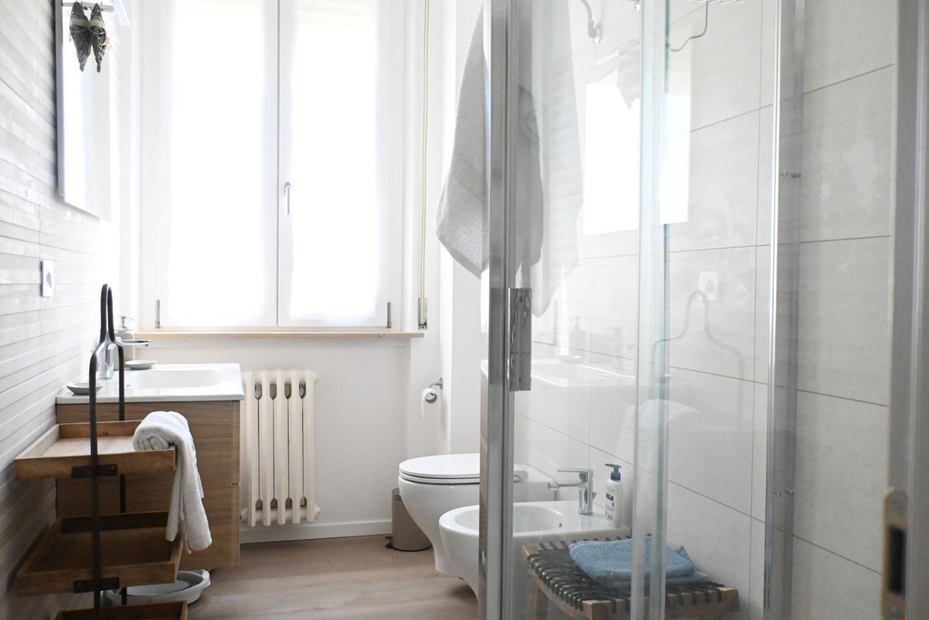 Ein modernes Badezimmer mit Duschkabine, Toilette, Waschbecken und Handtuchheizkörper.