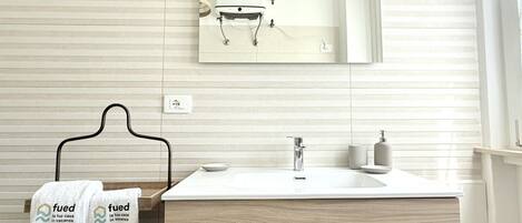 A bathroom with a large mirror, a sink, and a towel rack with two towels.