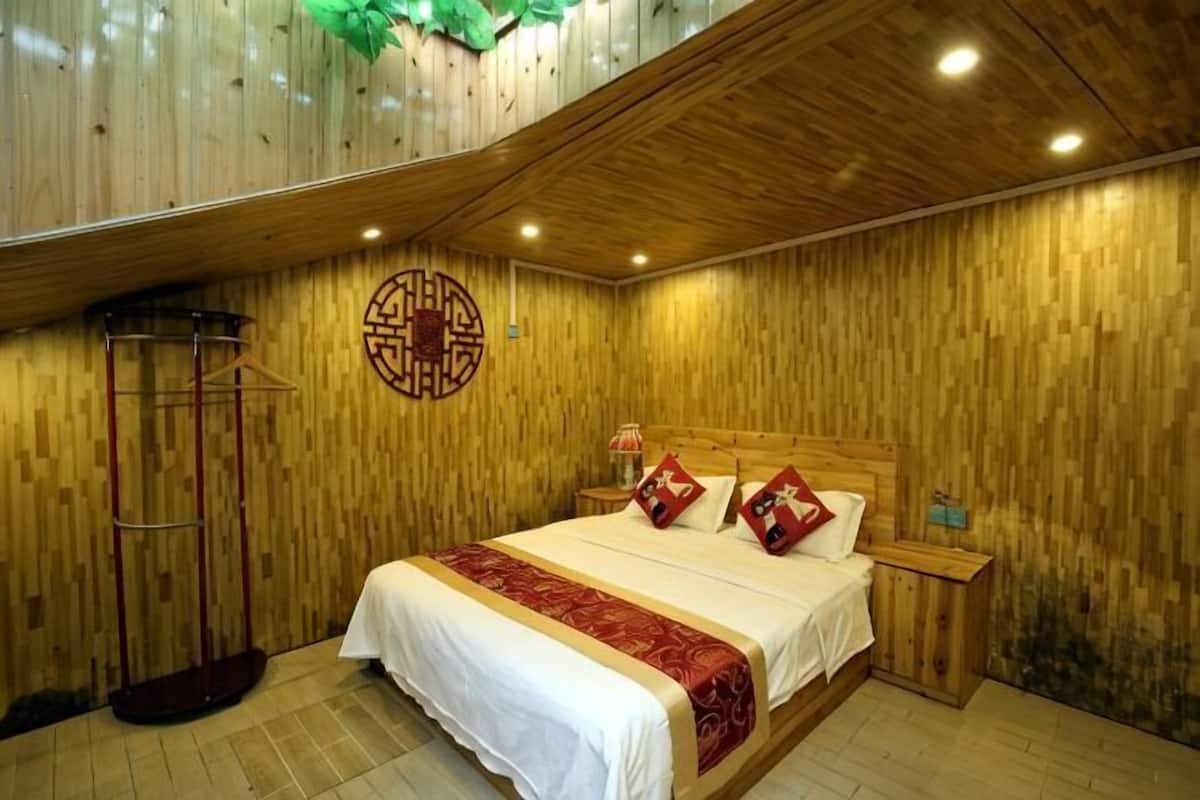 A wooden-paneled room with a bed, a nightstand, and a hanging coat rack.
