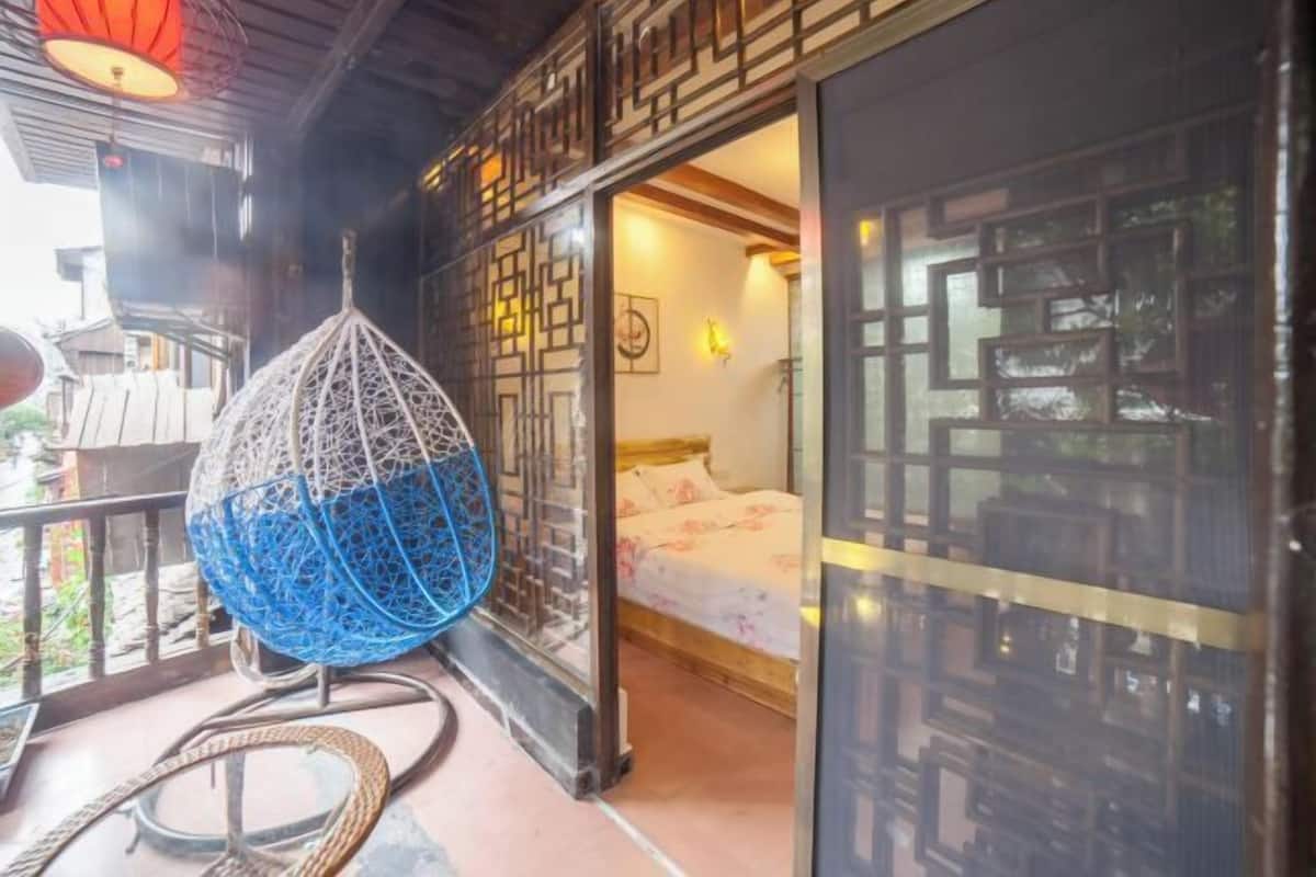 A traditional room with a bed, a hanging chair, and a view of the outside.