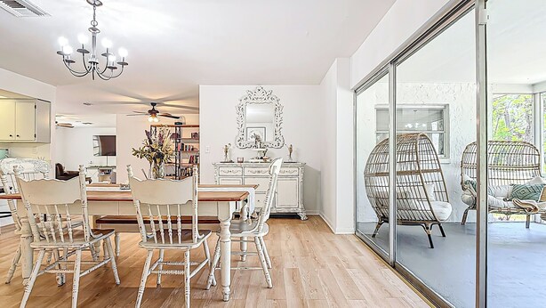 Un comedor amplio con una mesa y sillas de madera, un candelabro y un espejo grande sobre la mesa.