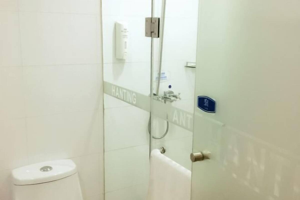 A bathroom with a glass partition, a toilet, and a shower area.