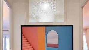 Een gang met een groot abstract schilderij aan de muur, een vloerbedekking en een deur die naar een andere kamer leidt.