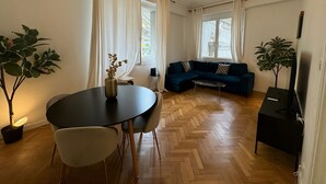 Een moderne woonkamer met een ronde eettafel, een bank en twee potplanten.