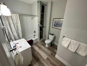 A modern bathroom with a shower, toilet, and sink.