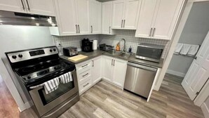 A modern kitchen with white cabinets, stainless steel appliances, and a tiled backsplash.