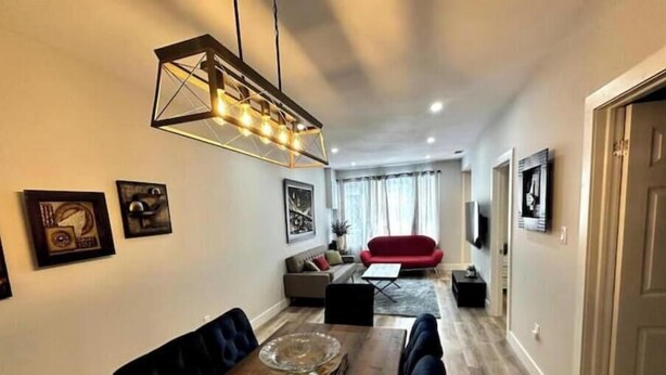 A dining area with a wooden table, chairs, and a modern pendant light.