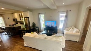 A modern living room with a sofa, a TV, and a dining area with a table and chairs.