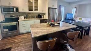 A modern kitchen with a central island, stainless steel appliances, and a dining area with a TV.