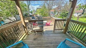 A wooden deck with two blue chairs, a table, and a red chair.