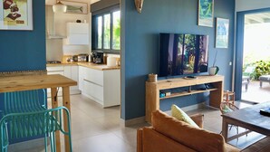 A modern living room with a TV, sofa, and dining area. - Villa Acacias, Villa Acacias, piscine et vue panoramique (L'Étang-Salé)