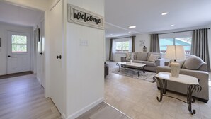 A modern living room with a sofa, coffee table, and a 'Welcome' sign on the wall. - Riverfront Stay |Deck, Views & Outdoor Living (Bird In Hand)