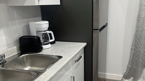 Une cuisine moderne équipée d’un évier en acier inoxydable, d’une machine à café et d’un réfrigérateur noir.