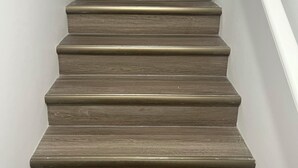 Un escalier en bois avec une rampe blanche et des murs blancs.