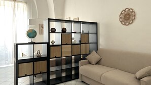 A modern living room with a beige sofa, a black and white shelving unit with decorative items, and a globe on a side table.