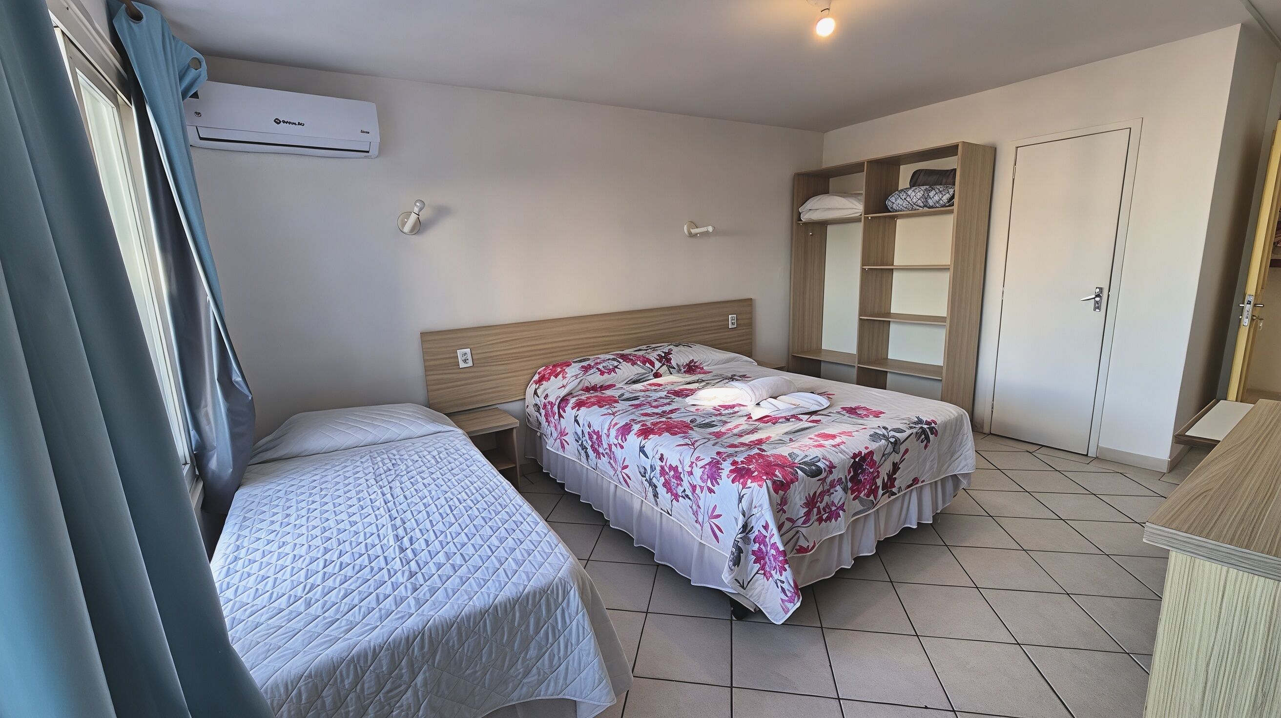 Une chambre avec deux lits, une armoire et un appareil de climatisation.