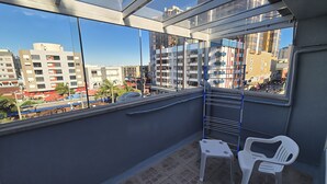 A balcony with a view of a cityscape, a metal railing, and two white plastic chairs. - Hotel Kolman (Capao da Canoa)