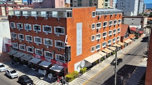 A multi-story hotel with a brick facade, multiple windows, and outdoor seating areas. - Hotel Kolman (Capao da Canoa)