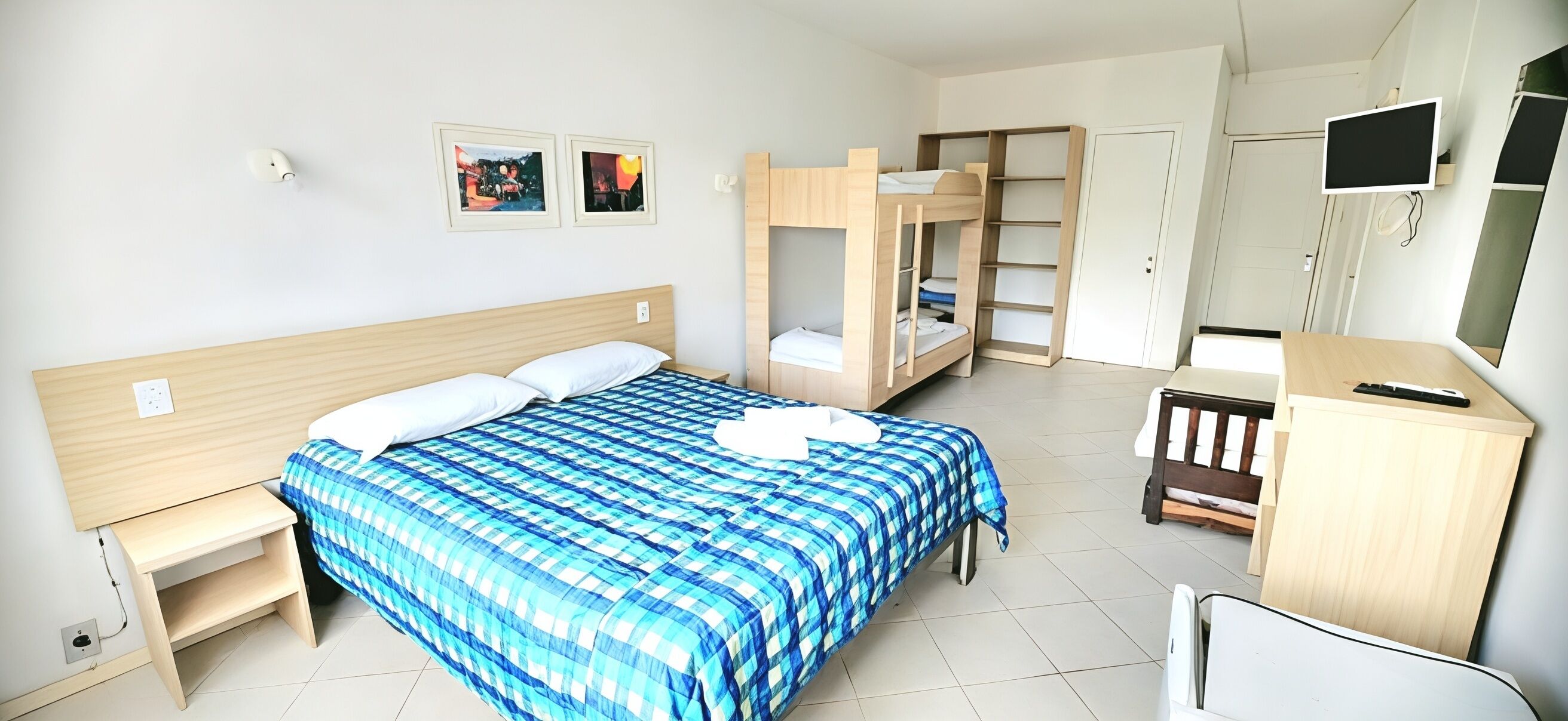 Un dormitorio con cama, literas, escritorio, silla, televisor y armario.