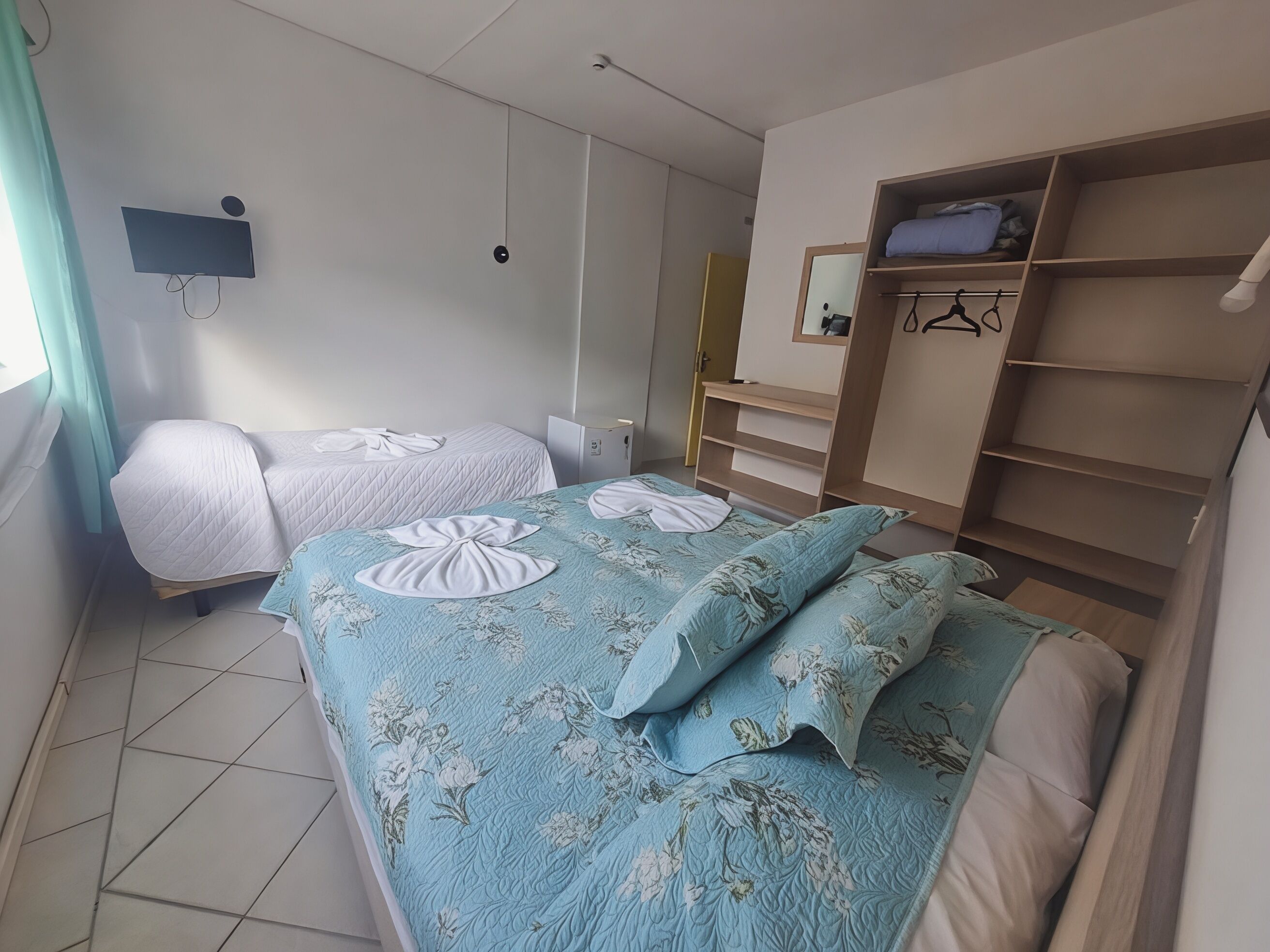 Un dormitorio con dos camas, un armario, un espejo y un televisor.