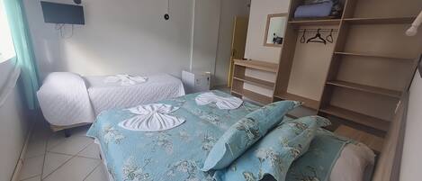 Un dormitorio con dos camas, un armario, un espejo y un televisor.