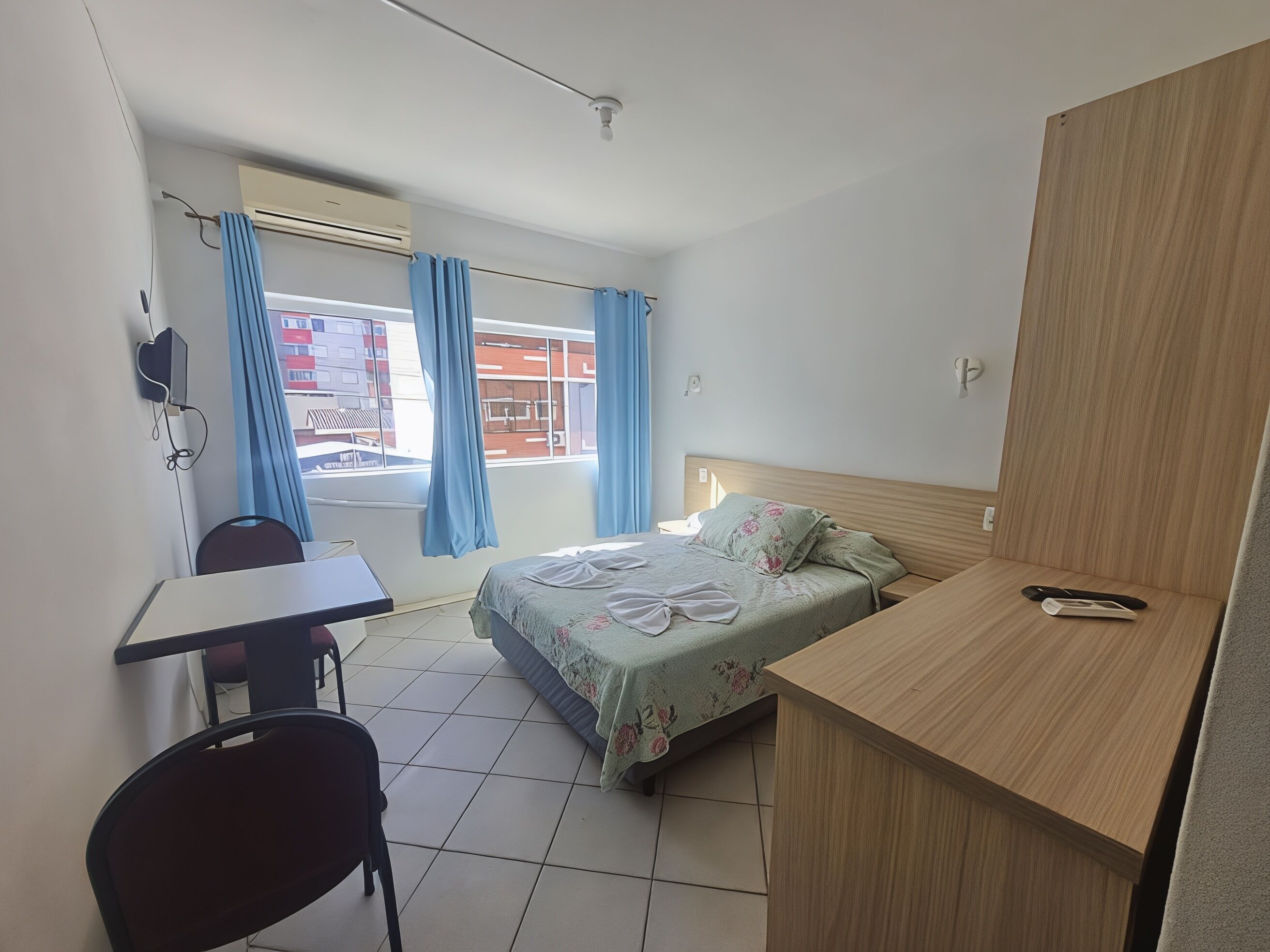 Una camera d'albergo con un letto, una scrivania, una sedia e vista sull'esterno.