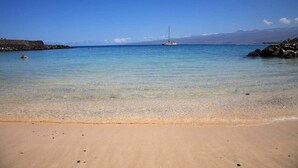 A beach with clear water, a sailboat, and rocky terrain. - Mauna Lani Resort  Terrace - G301 - BEST VIEWS - Updated - Owners Club Access (Kamuela)