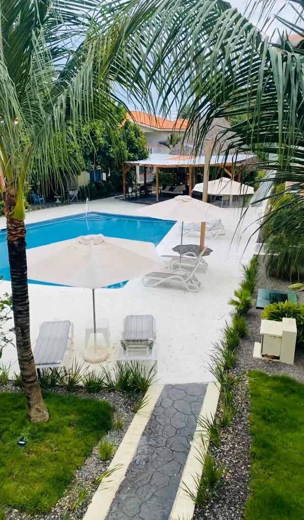 A pool area with lounge chairs and a covered seating area.