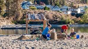 A sandy beach with children playing and a wooden structure with fish.